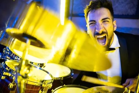 The Gloves drummer playing behind a cymbal under yellow stage lights