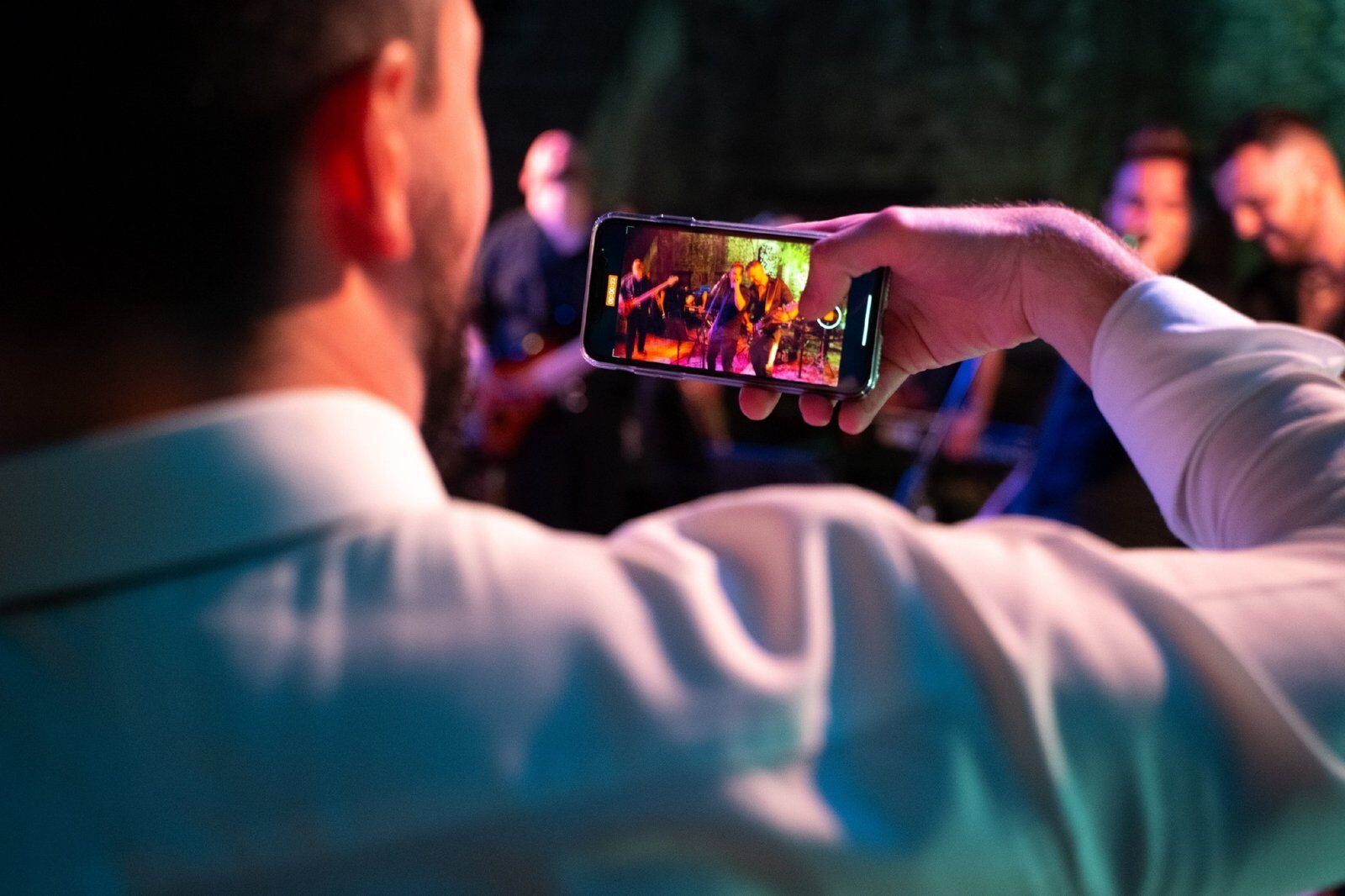 Wedding guest filming the live band with a smartphone during a high-energy performance