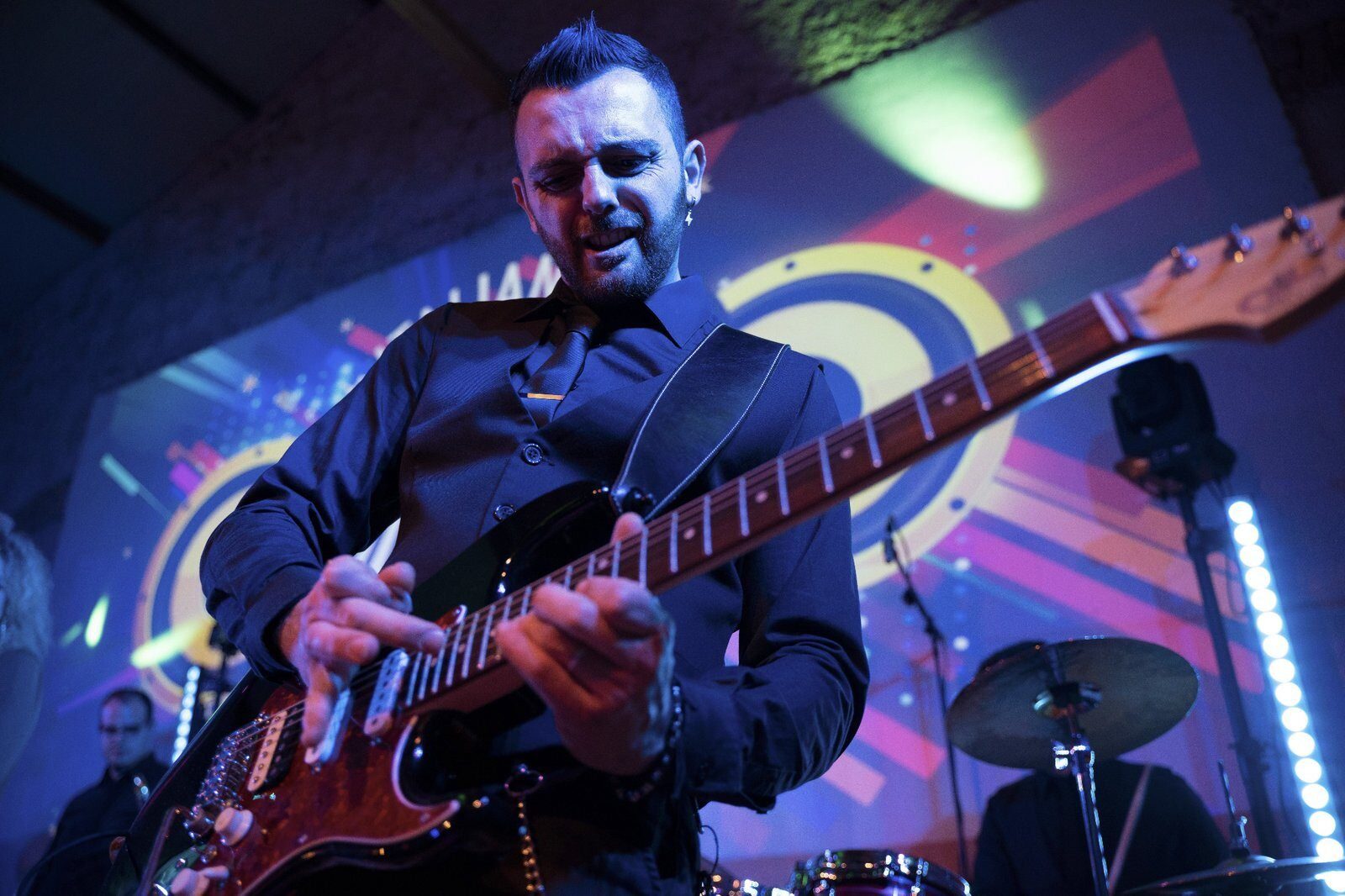 Wedding band guitarist performing a live solo on stage during a wedding party in Italy